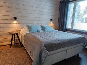 a bedroom with a bed with a wooden wall at Rantatähti Villa in Syöte