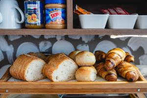 a shelf with various types of bread and croissants at Privilege Suite Pieta in Tal-Pietà