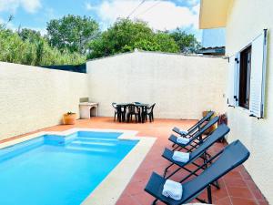 un patio con 2 sillas y una piscina en Beach & Pool House @ Mindelo en Vila Chã