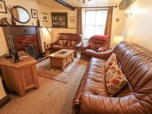 a living room with leather furniture and a fireplace at Springwell Cottage in Ambleside