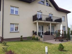 a white house with a deck and a bench at Villa Spokojna 26 in Mielno