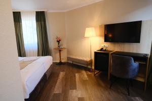 a hotel room with a bed and a desk with a television at PARKHOTEL - Rosarium in Uetersen