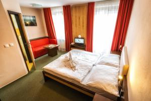 ein Hotelzimmer mit einem Bett und einem roten Sofa in der Unterkunft Hotel Malina*** in Ružomberok
