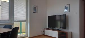 a living room with a flat screen tv and two windows at Słoneczne, komfortowe z osobą kuchnią in Gdańsk