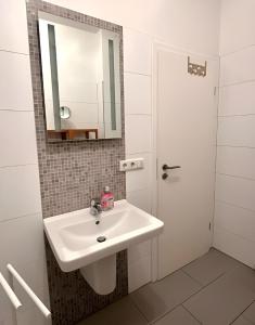 ein weißes Badezimmer mit einem Waschbecken und einem Spiegel in der Unterkunft RAHA - Historischer Charme direkt am Domplatz in Erfurt