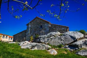 an old stone church with rocks in front of it at Casa Lela Dumbria in Dumbría