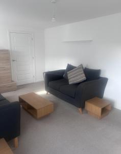 uma sala de estar com um sofá preto e mesas de madeira em Solihull Guest House 1 em Olton