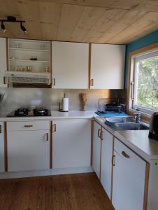a kitchen with white cabinets and a sink and a window at Chalet 9 personnes, piscine, terrasse in Saint-Maurice-sur-Moselle