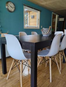 a dining room with a black table and white chairs at Chalet 9 personnes, piscine, terrasse in Saint-Maurice-sur-Moselle