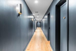 a long hallway with blue walls and a wooden floor at The Phenix, Historic DTWN Hotel, Market Square View, King Bed, Room # 400 in Bangor