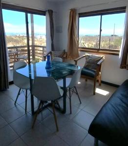 uma sala de jantar com uma mesa de vidro e cadeiras em Atardeceres Tongoy - Cabaña 4 personas condominio privado Tanguemar em Coquimbo