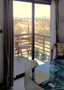 Habitación con vistas a un balcón con mesa de cristal y silla. en Atardeceres Tongoy - Cabaña 4 personas condominio privado Tanguemar en Coquimbo