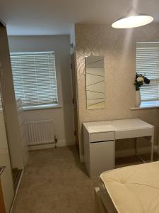 a bedroom with a table and a mirror and two windows at Inviting 2-Bed Apartment in Bushey in Bushey