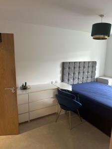 a bedroom with a blue bed and a chair at Inviting 2-Bed Apartment in Bushey in Bushey