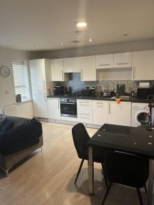 a kitchen with white cabinets and a table and a couch at Inviting 2-Bed Apartment in Bushey in Bushey