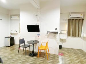 a room with a table and chairs and a tv at The Alex in Ban Don Muang (1)