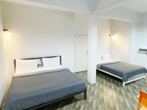 two beds in a room with white walls at The Alex in Ban Don Muang