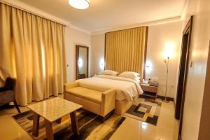 a bedroom with a bed and a chair and a table at MEETHAQ HOTELS MAITAMA in Abuja