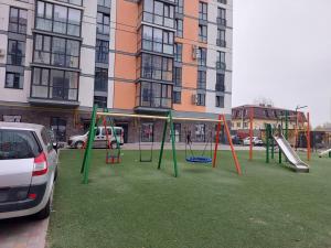 a playground in front of a building withweredwered swings at DreamTown Однокімнатна біля вокзалу in Lutsk