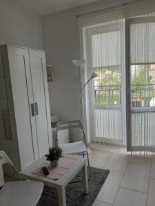 a white living room with a table and a chair at Villa Spokojna 26 in Mielno