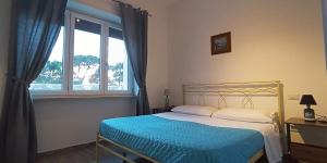 a bedroom with a bed with a blue blanket and a window at La casa di pinocchio in Bacoli