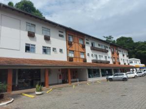 un bâtiment avec des voitures garées dans un parking dans l'établissement CHA Mime Hotel, à Blumenau