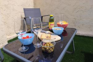 a table with wine glasses and bowls of food at Le Patio - Spacieux et lumineux T3 - 15 min centre pieds in Bergerac