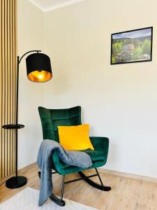 een groene stoel met een geel kussen en een lamp bij Harzburgliving Wohnung Goethe`s Auszeit in Bad Harzburg