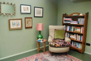 a living room with a chair and a book shelf at Little Cottage Shipton in Shipton under Wychwood