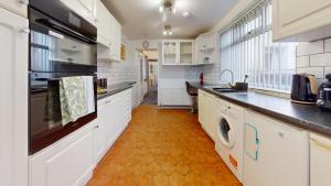 uma cozinha com armários brancos e um piso laranja em Modernised 3-bedroom Blackburn townhouse sleeps 6 em Rishton