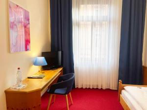 a hotel room with a desk with a computer and a bed at Hotel Restaurant Krokodil in Heidelberg