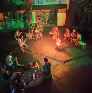 a group of people sitting around a fire at Rosa dos Ventos Hostel in Boicucanga