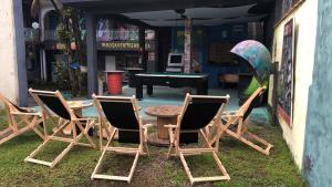 um grupo de cadeiras e uma mesa de pingue-pongue num quintal em Rosa dos Ventos Hostel em Boiçucanga