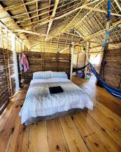 Private Traditional Hut on the water with 2 rooms في Wichubualá: سرير في غرفة مع أرجوحة