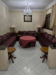 ein Wohnzimmer mit Sofas, einem Tisch und einem Kronleuchter in der Unterkunft Appartement médina Salé in Salé