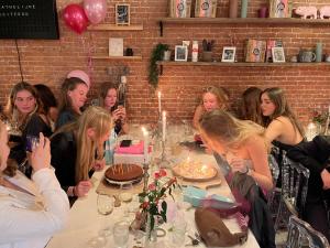 a group of women sitting around a table with a cake at HOMESTEAD Amsterdam in Amsterdam