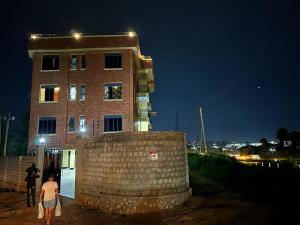 two people walking past a brick building at night at Durlan metroplex in Kampala