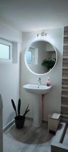 uma casa de banho com um lavatório branco e um espelho. em Cosy Garden Studio em Messini