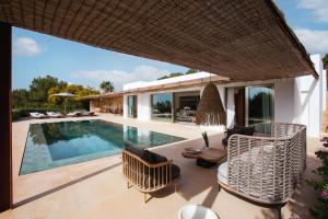 an outdoor patio with chairs and a swimming pool at Villa Turquesa in Es Cubells +26 photos