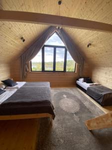 two beds in a room with a large window at Dom wakacyjny nad jez Orzysz in Orzysz