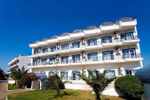 a white building with balconies and trees in front of it at Ares Blue Hotel in Kemer