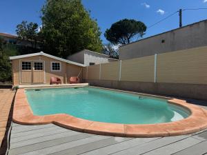 einen Pool mit einer Holzterrasse und einem Gebäude in der Unterkunft Charmante dépendance au centre historique à Agde in Agde