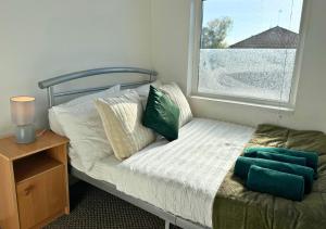 ein Bett mit Kissen und ein Fenster in einem Zimmer in der Unterkunft Cosy 2 Bed Apt For Families With Free Parking in Liverpool