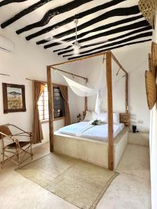 a bedroom with a canopy bed and a chair at Mlango Paje Villa Boutique in Paje