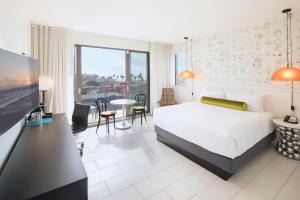 ロサンゼルスにあるHotel Erwin Venice Beachのベッド、テーブル、椅子が備わるホテルルームです。