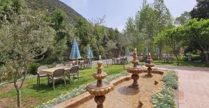 eine Reihe von Brunnen in einem Garten mit Tischen und Stühlen in der Unterkunft Top Ourika in Aghbalou