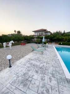 un patio con bancos, una piscina y una casa en Ktima Klimentini, en Vivari