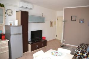 a living room with a tv and a table and a refrigerator at Casa Rosina + box per auto 2 bici 1,5km dalle mura in Lucca