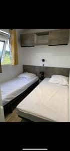 two twin beds in a room with a window at Camping Les Pins maritimes in Hyères