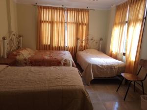 um quarto de hotel com duas camas e uma janela em HoSTAL SANTA BARBARA em Torotoro